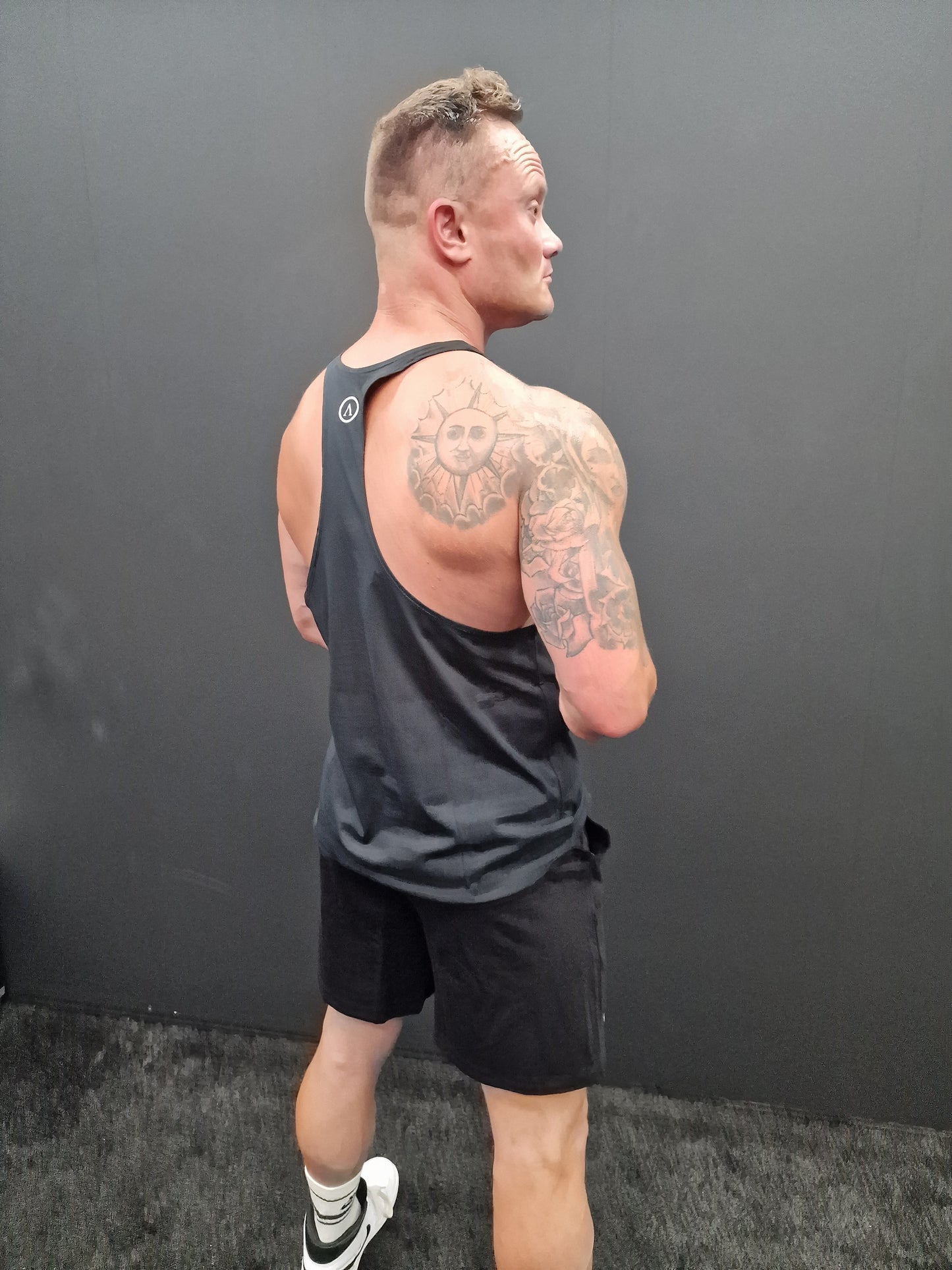 Man standing facing away from the camera, wearing a black Spartan Forge vest.