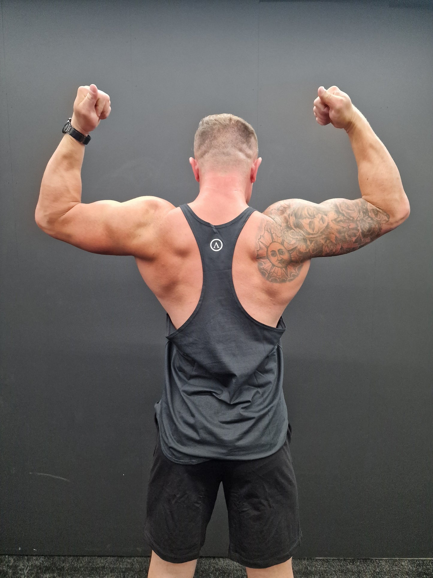 Man flexing his arm muscles against a gray background