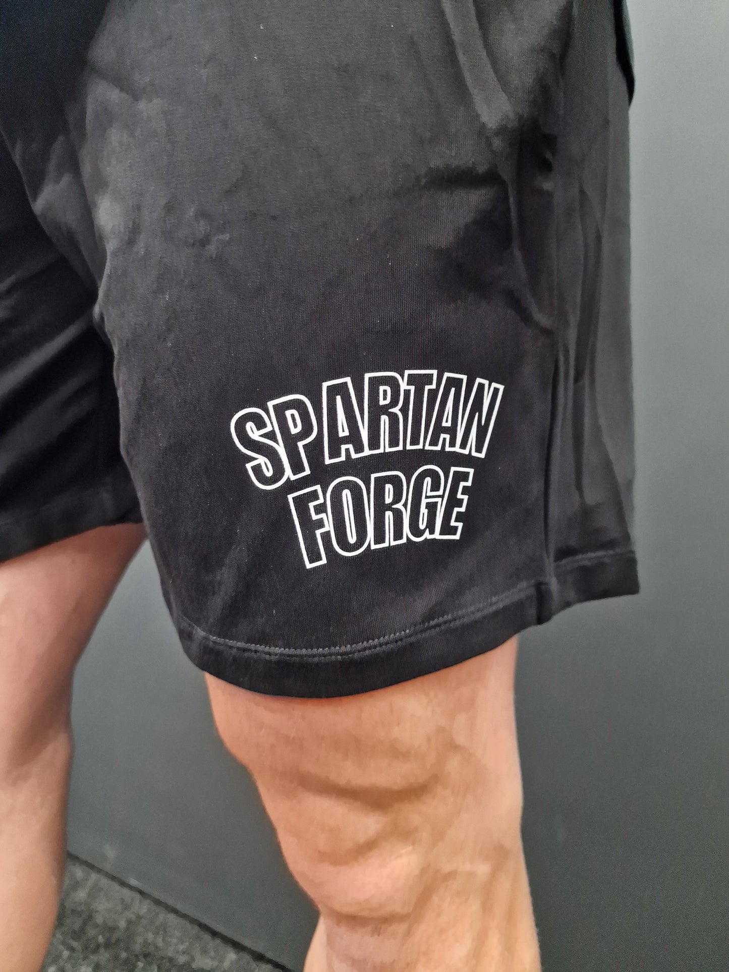 Black athletic shorts with 'Spartan Force' text on a person against a gray background